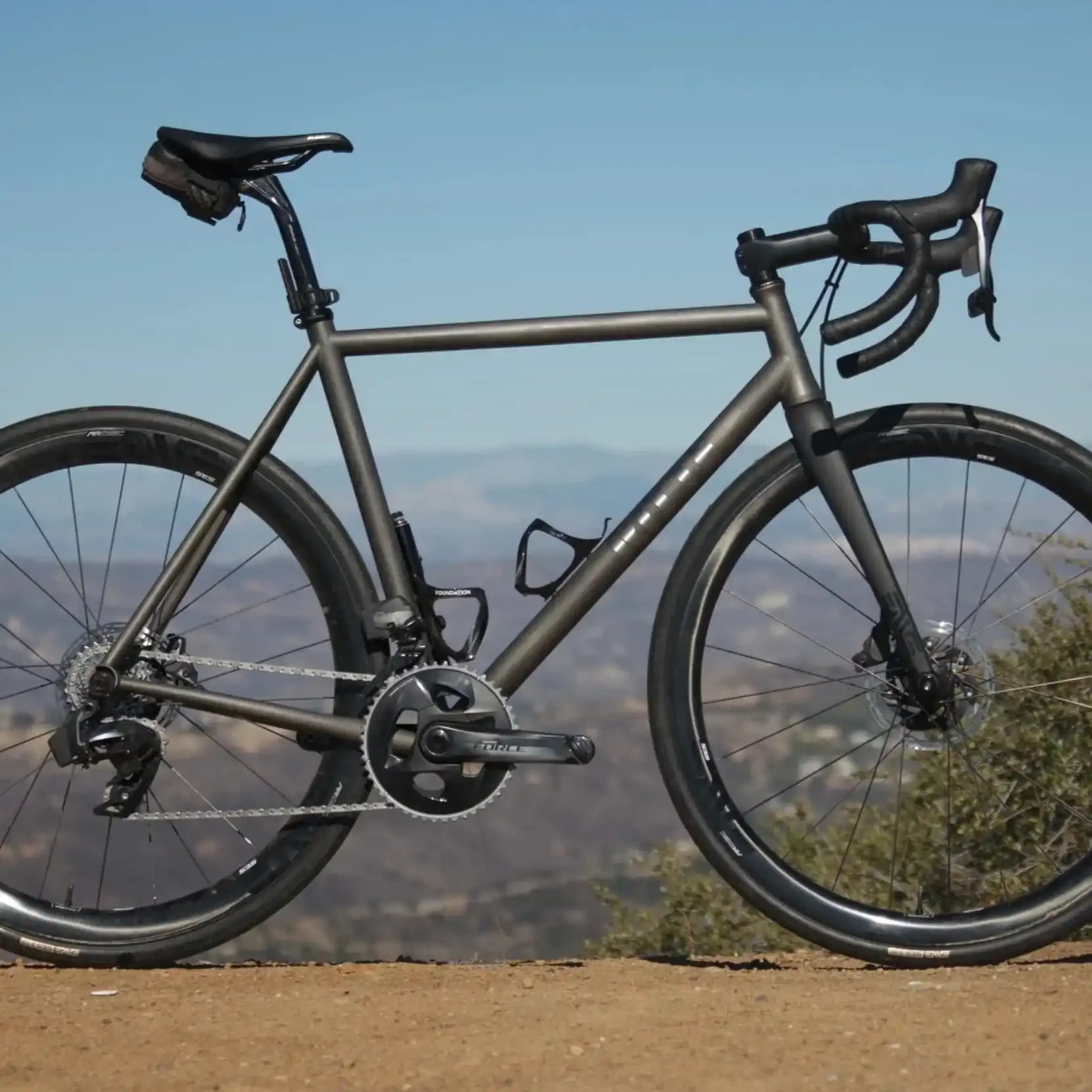 Gray titanium road bike with disc brakes and drop handlebars.