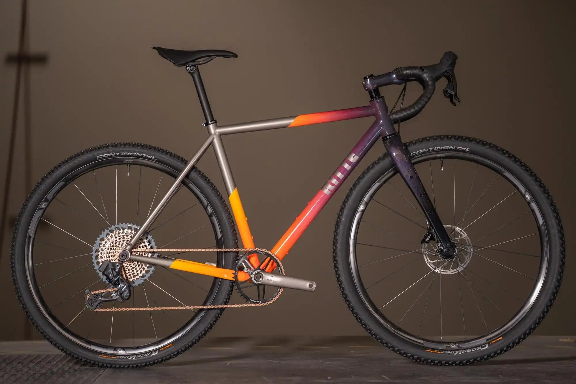 Modern gravel bike with a gradient paint scheme transitioning from purple to orange to white.