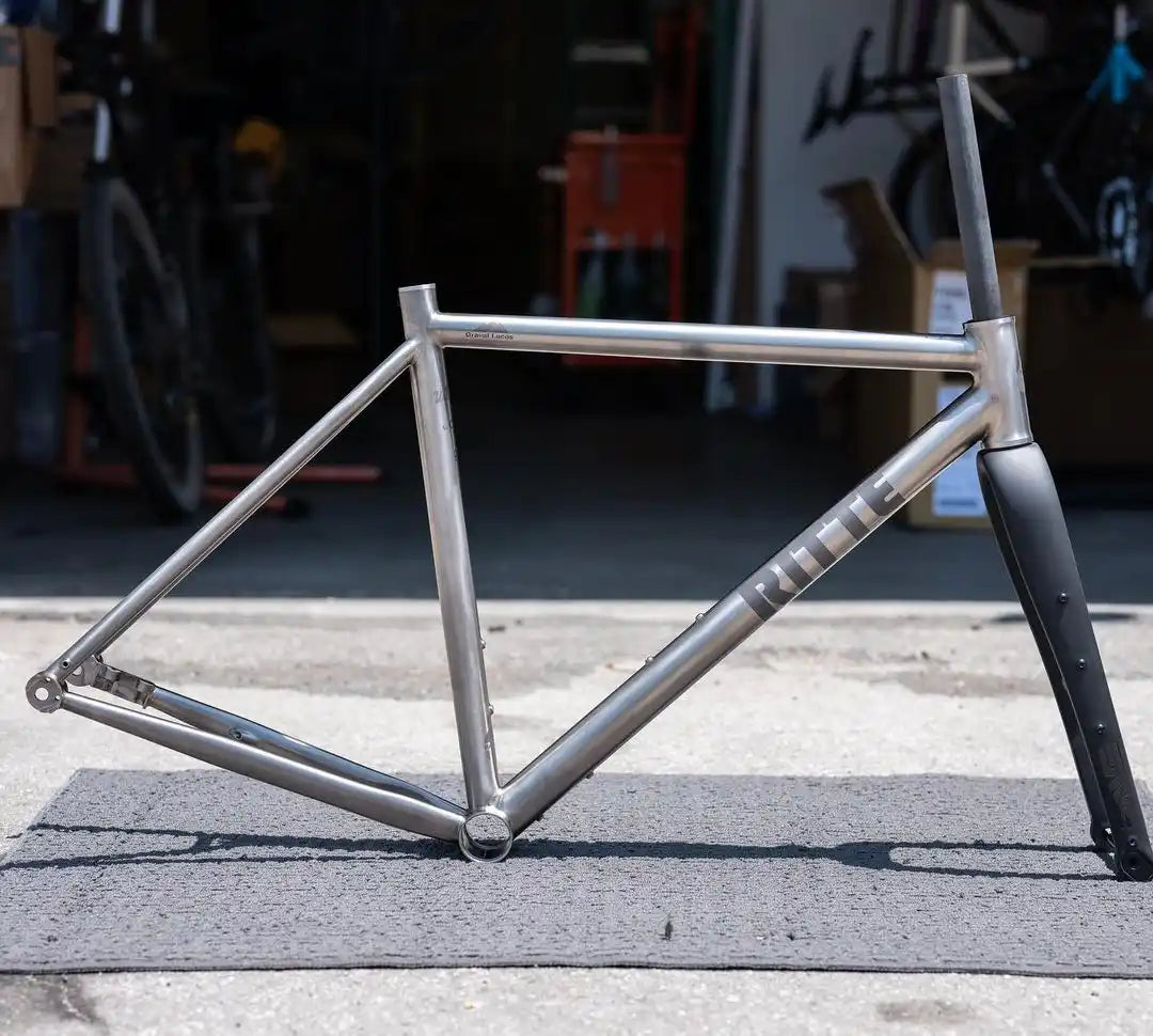 Raw titanium bicycle frame with black carbon fiber fork.