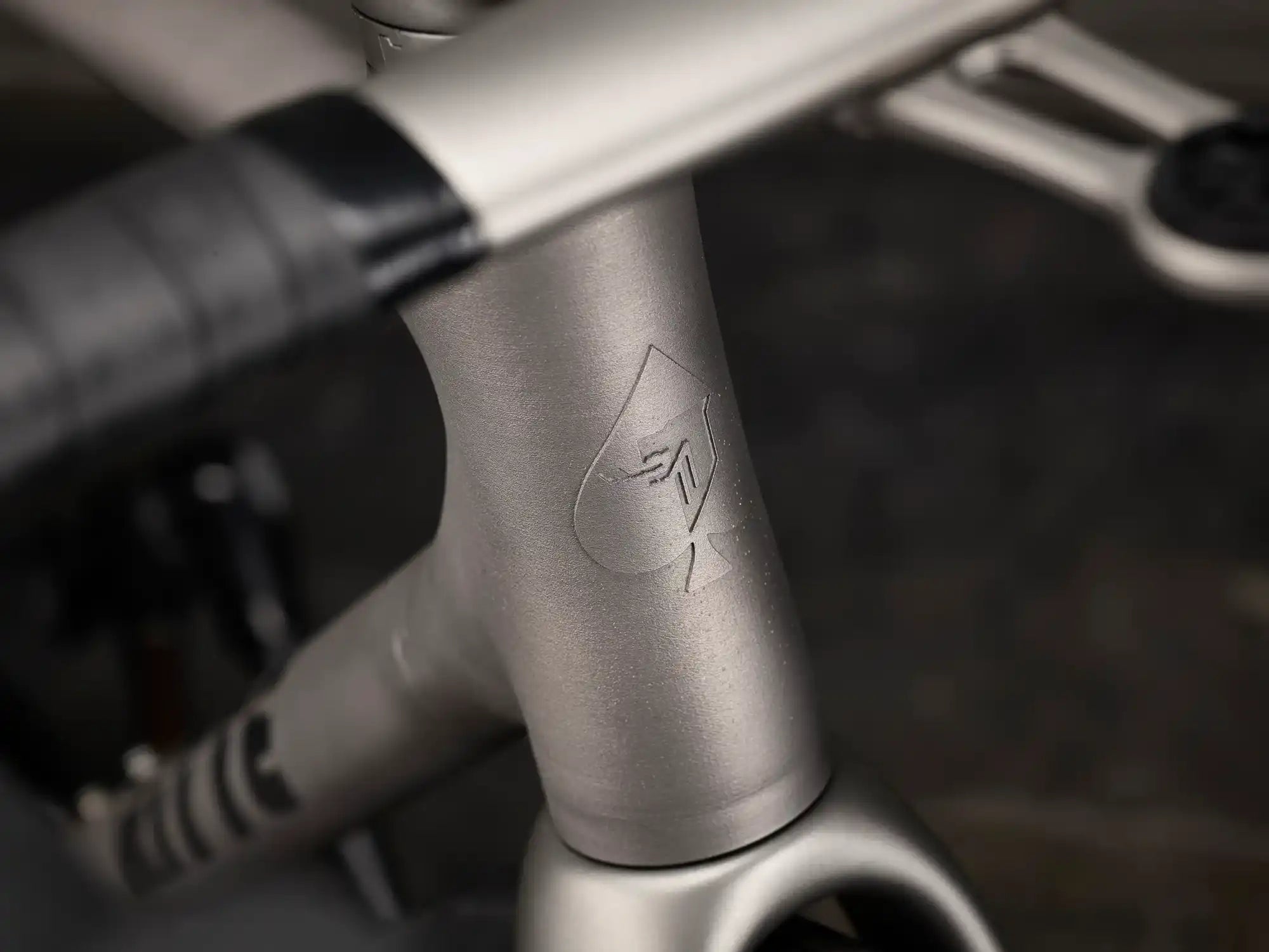 Silver bicycle frame tube with a subtle etched logo or marking.
