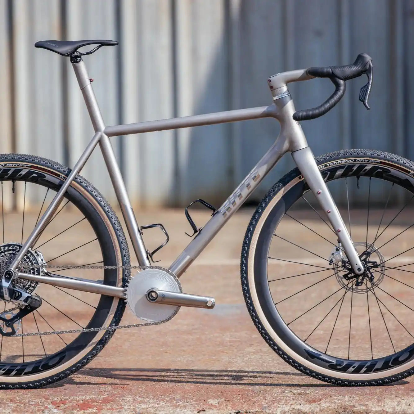 Silver gravel bicycle with disc brakes and drop handlebars.