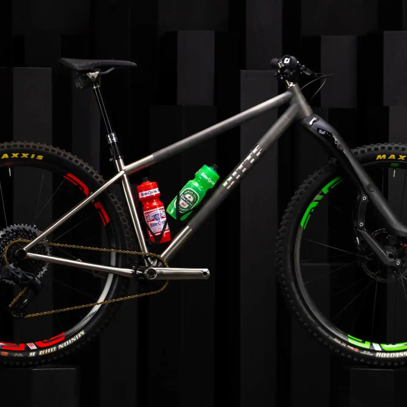 Titanium hardtail mountain bike with green and red accents.