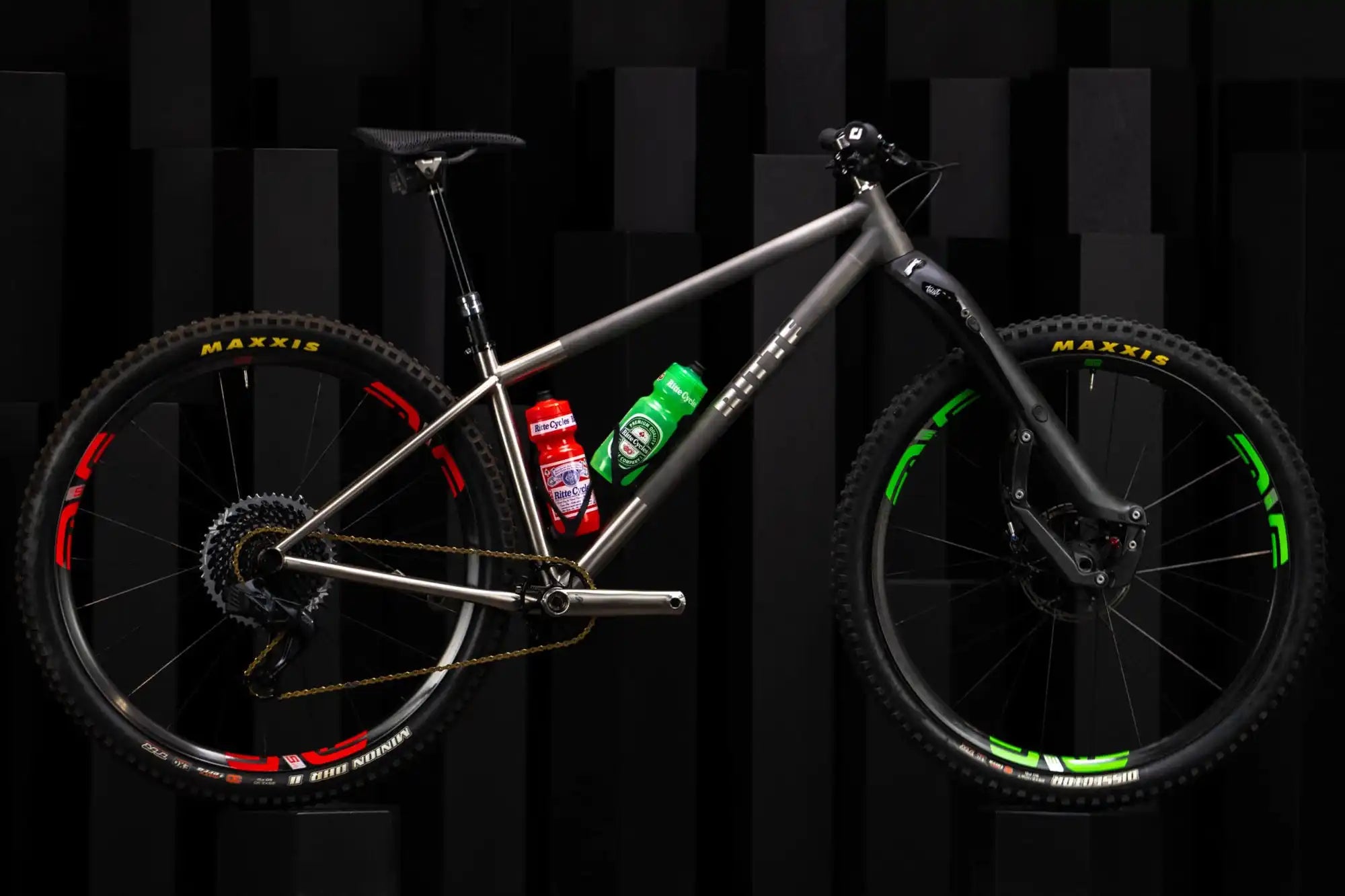 Titanium hardtail mountain bike with red and green accented wheels.