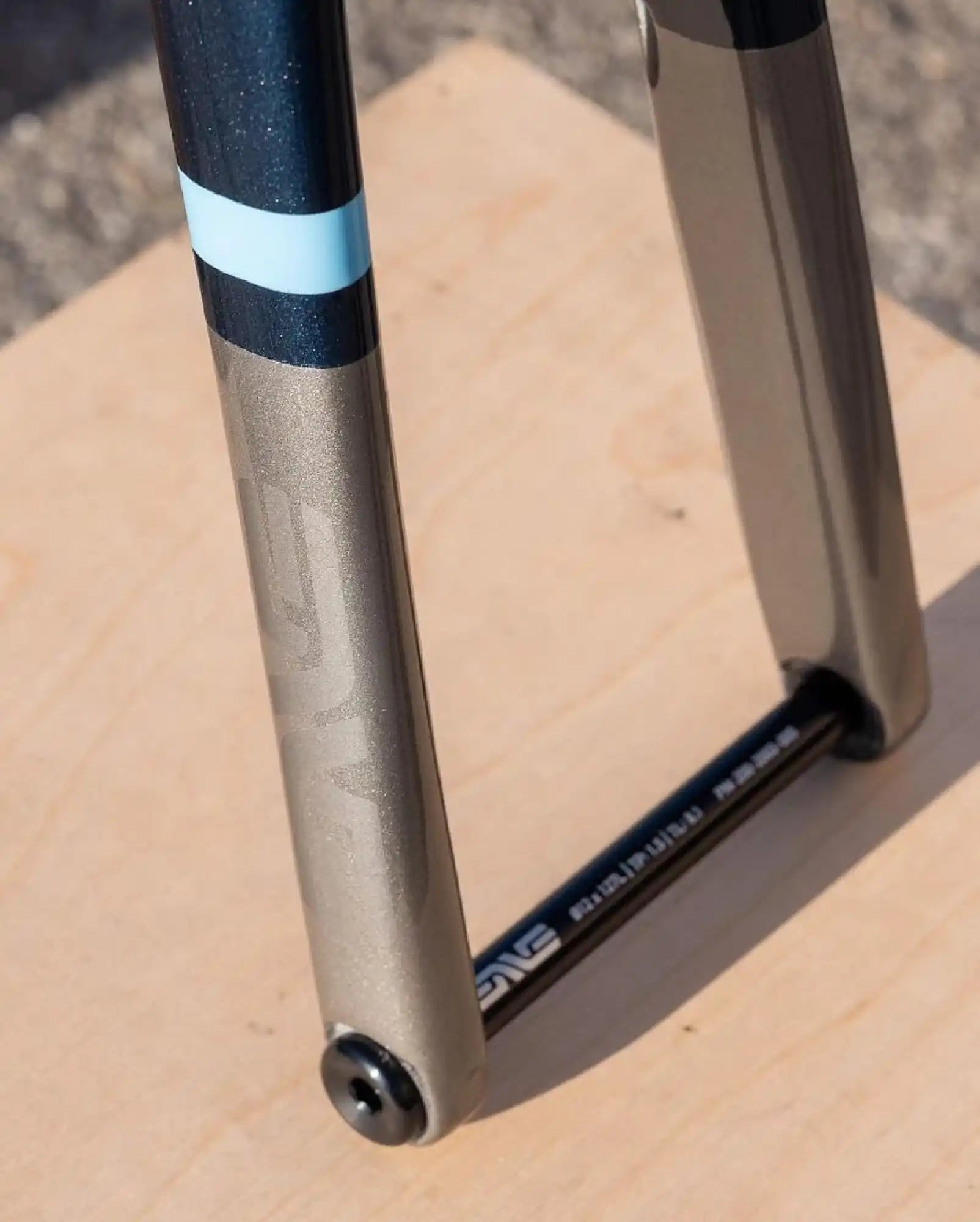 Bicycle fork with black and blue striped detailing on champagne-colored tubing.