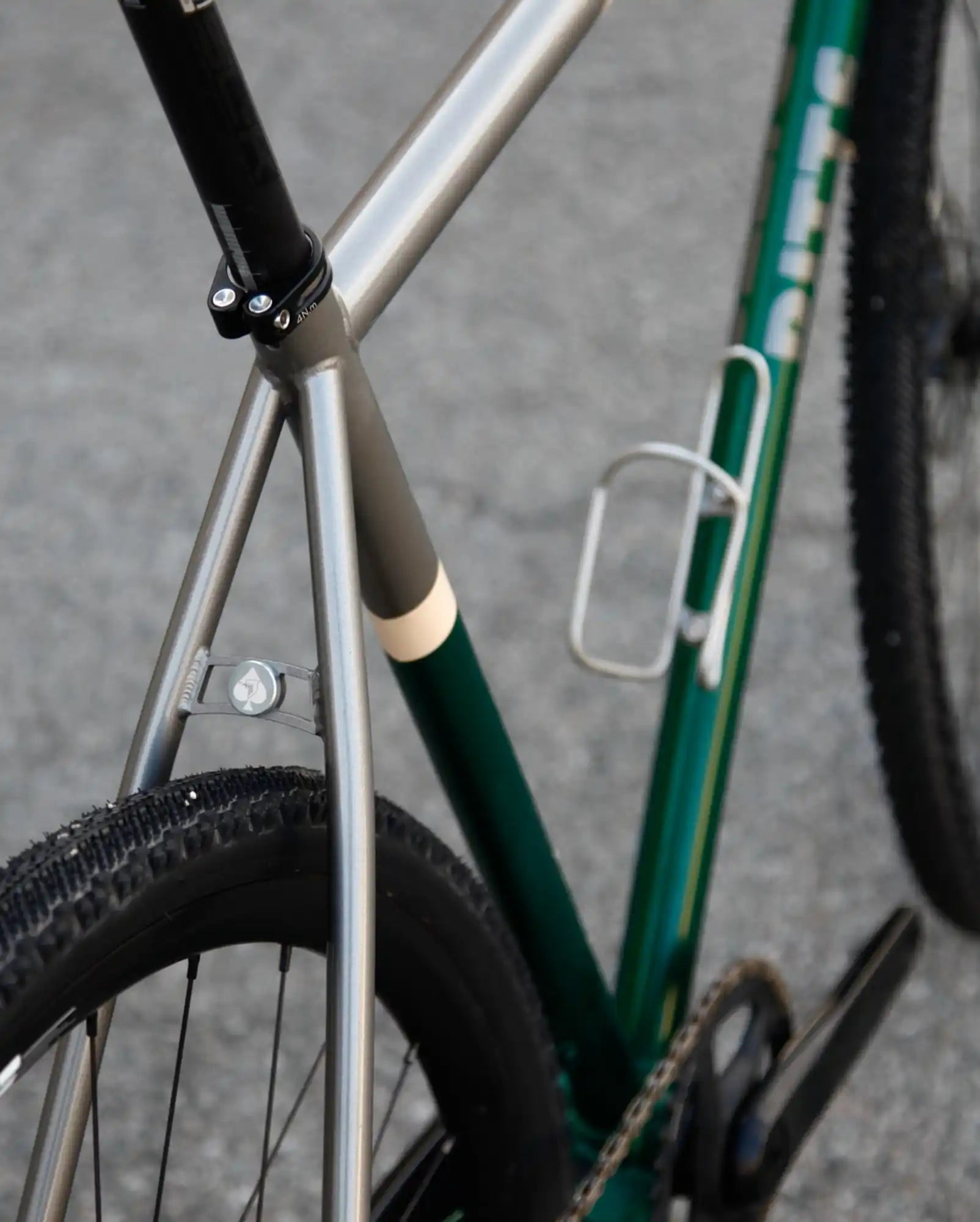 Bicycle frame detail showing a silver and green painted junction where the seat stays meet the seat tube.