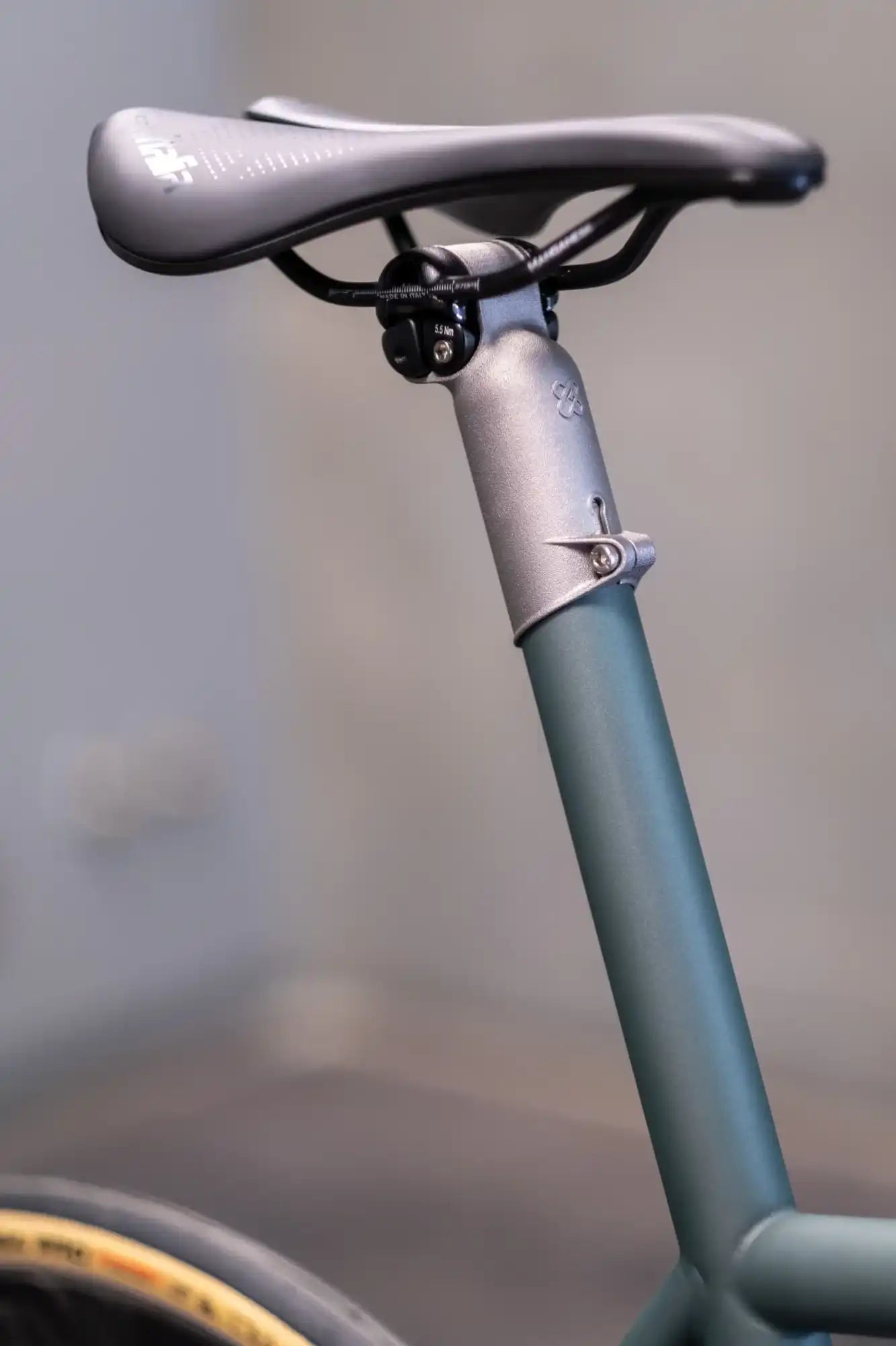 Bicycle seat post and saddle in matte gray and teal colors.