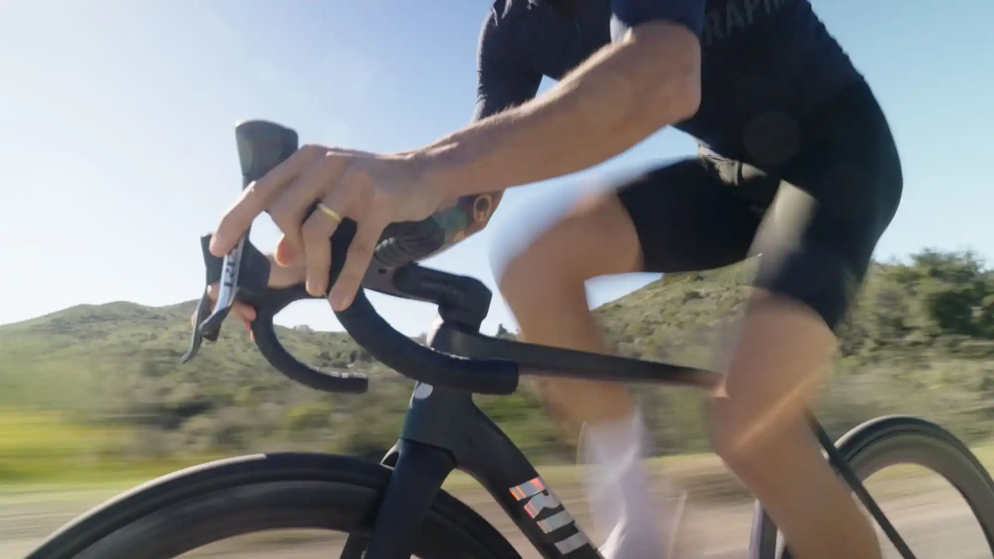 Black racing bicycle being ridden at speed.