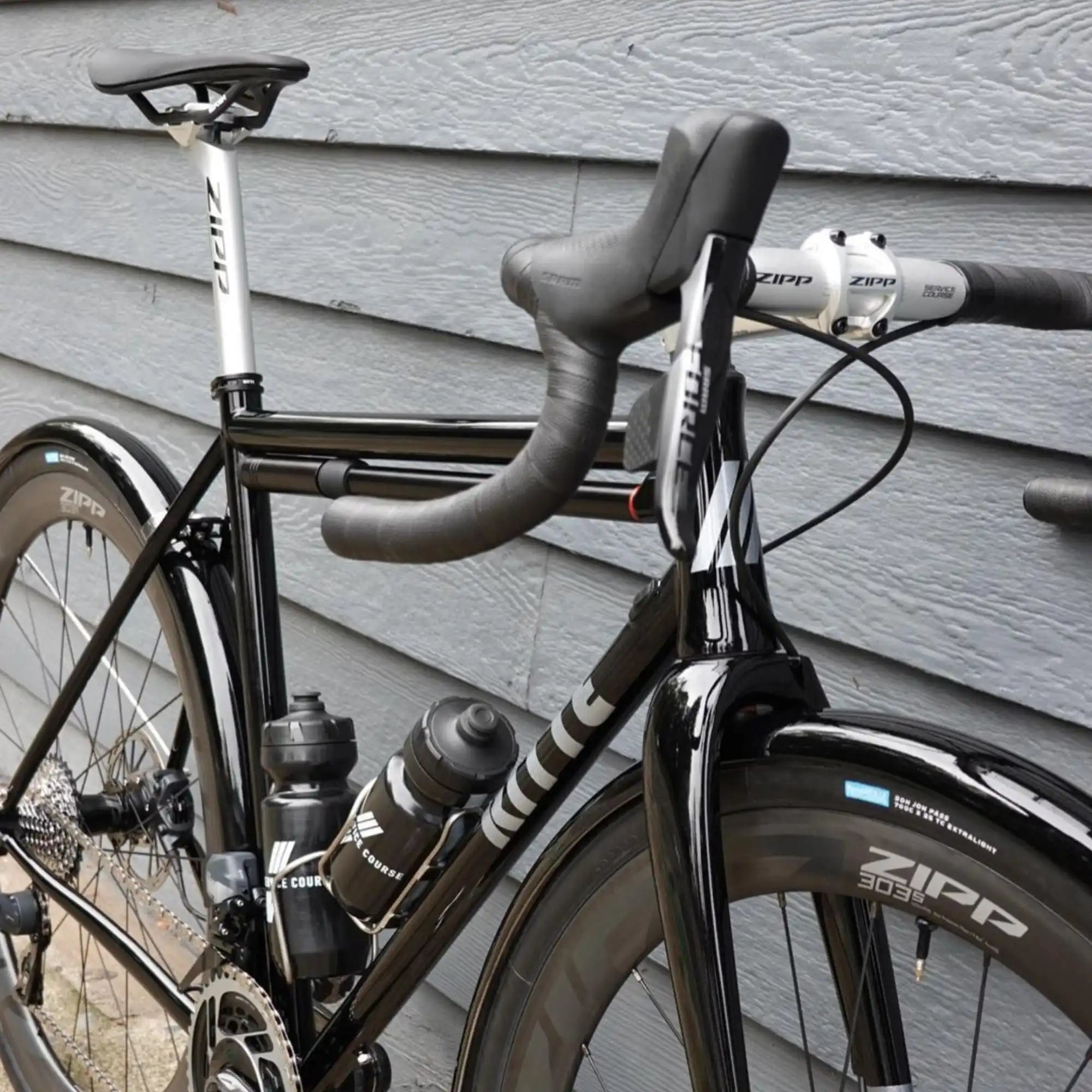 Black road bicycle with drop handlebars and water bottle cages.