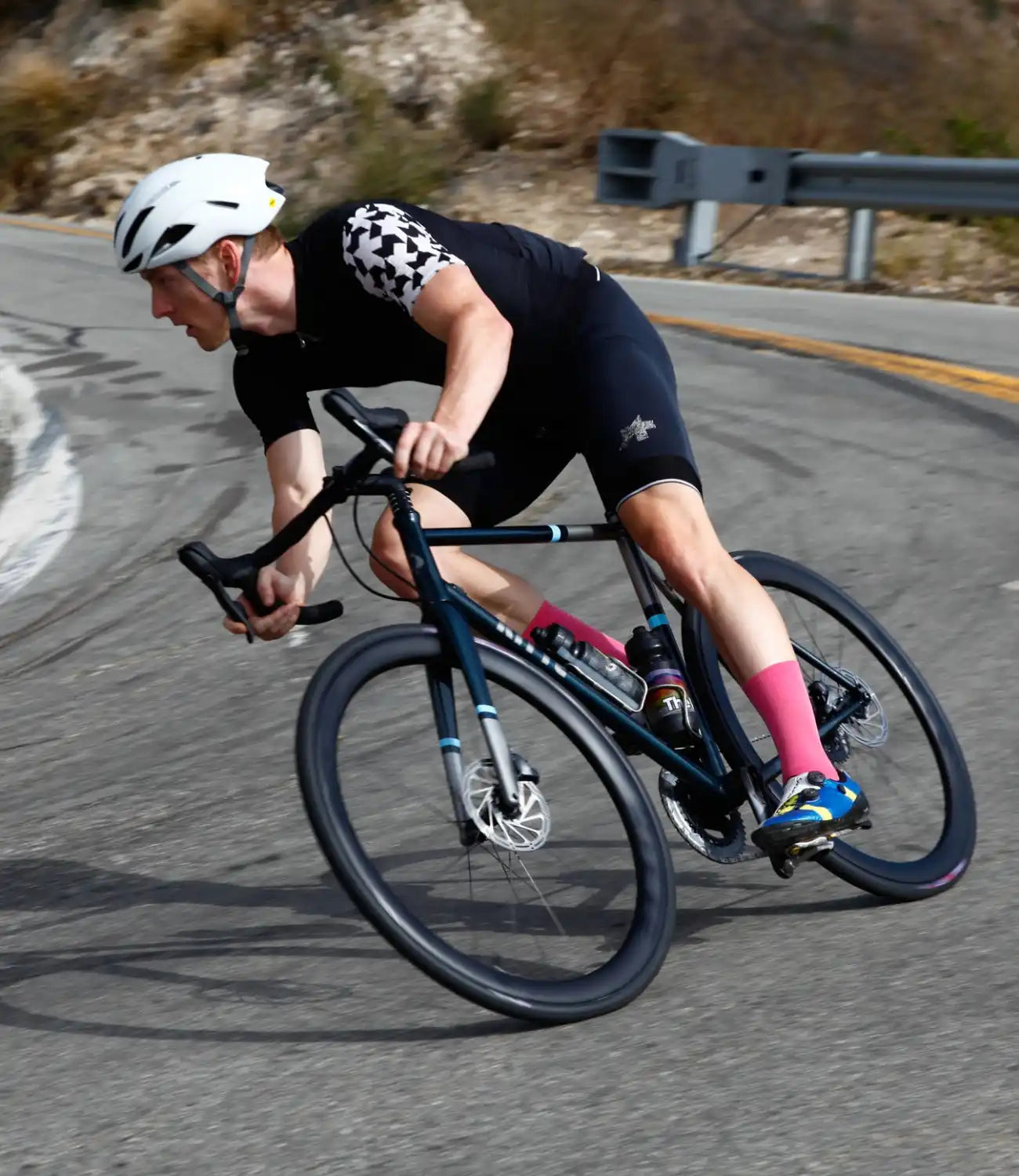 Cyclist in black attire leaning into a turn on a road bike.