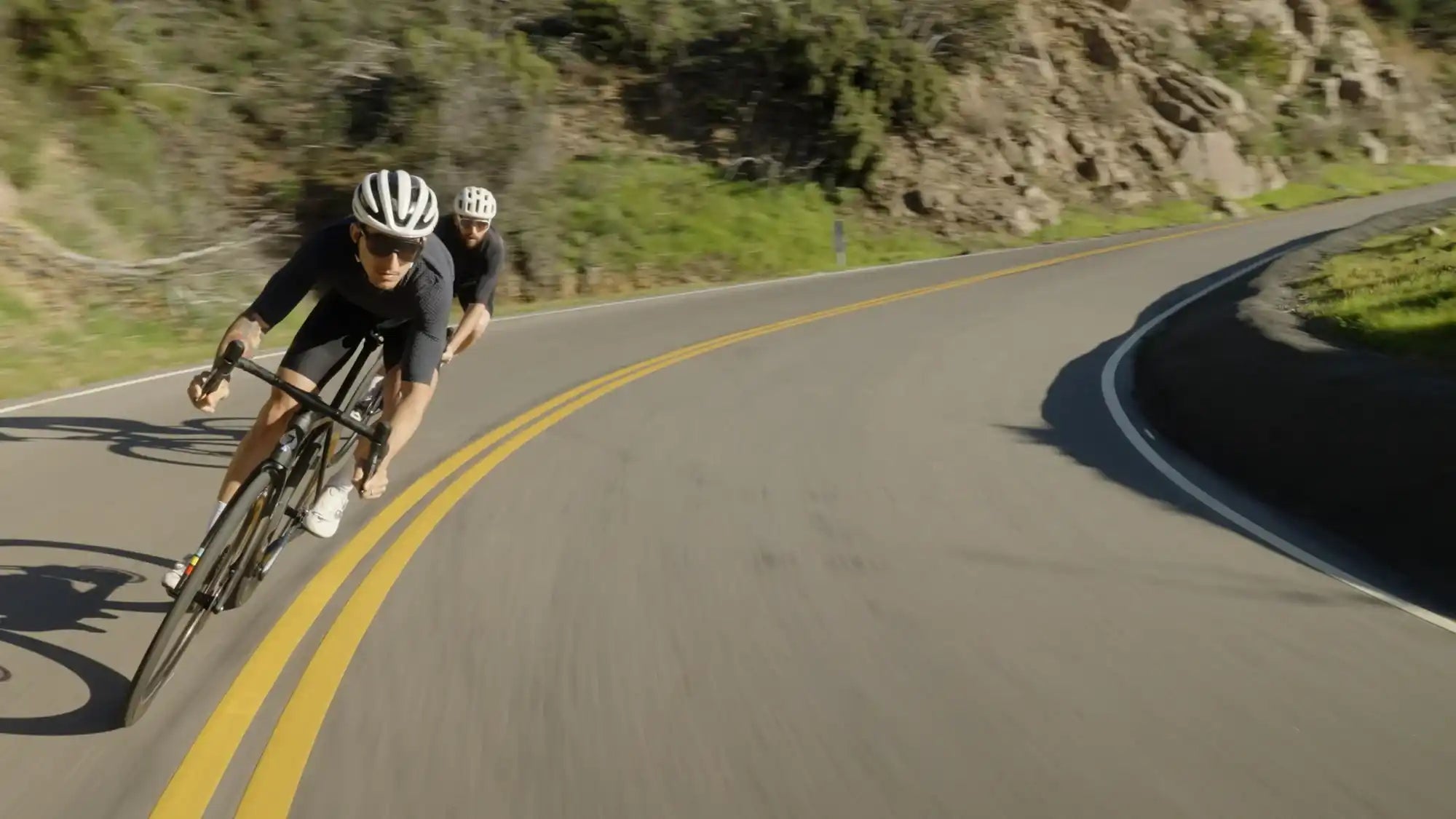 Cyclist in racing gear navigating a curved mountain road.