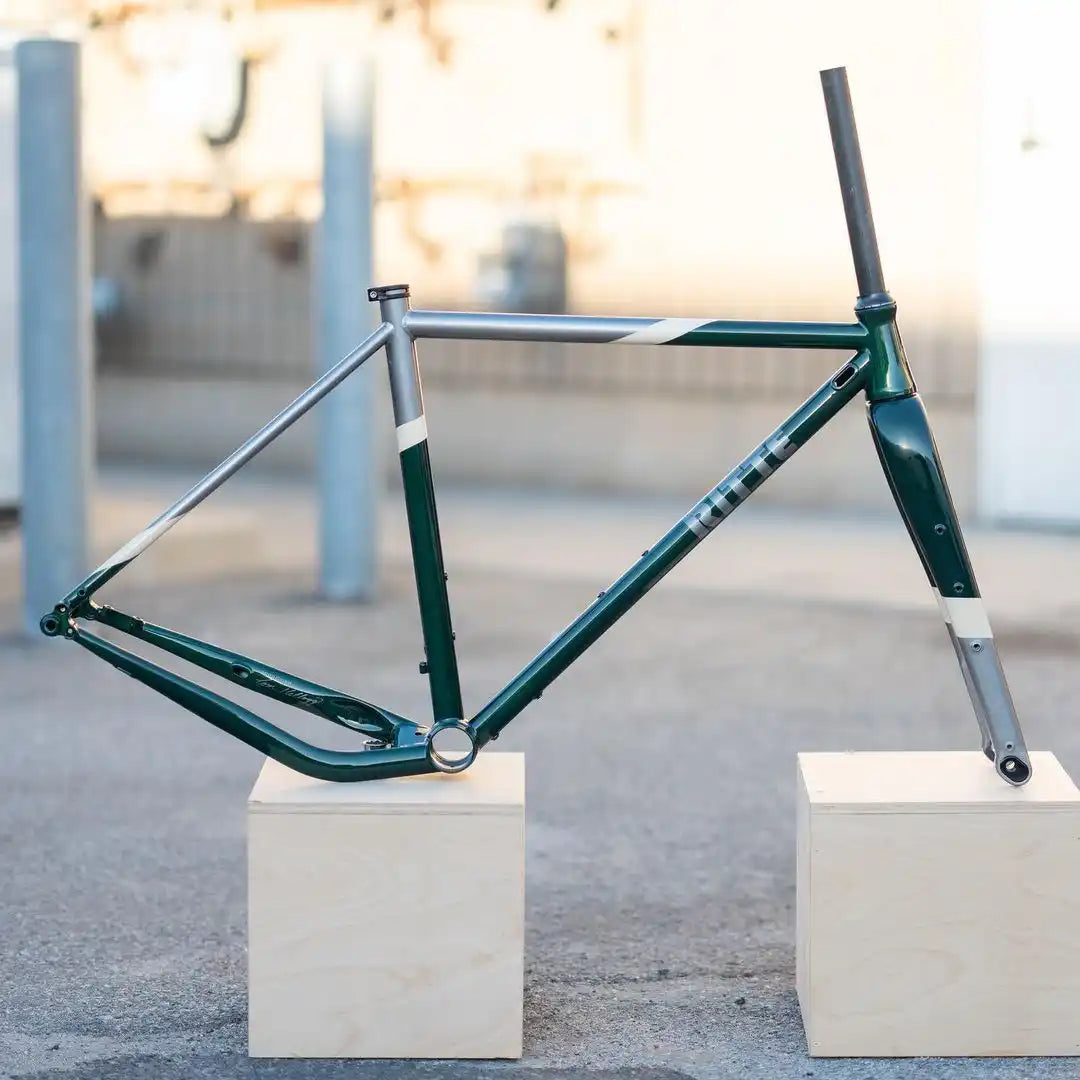 Dark green bicycle frame mounted on white display blocks.