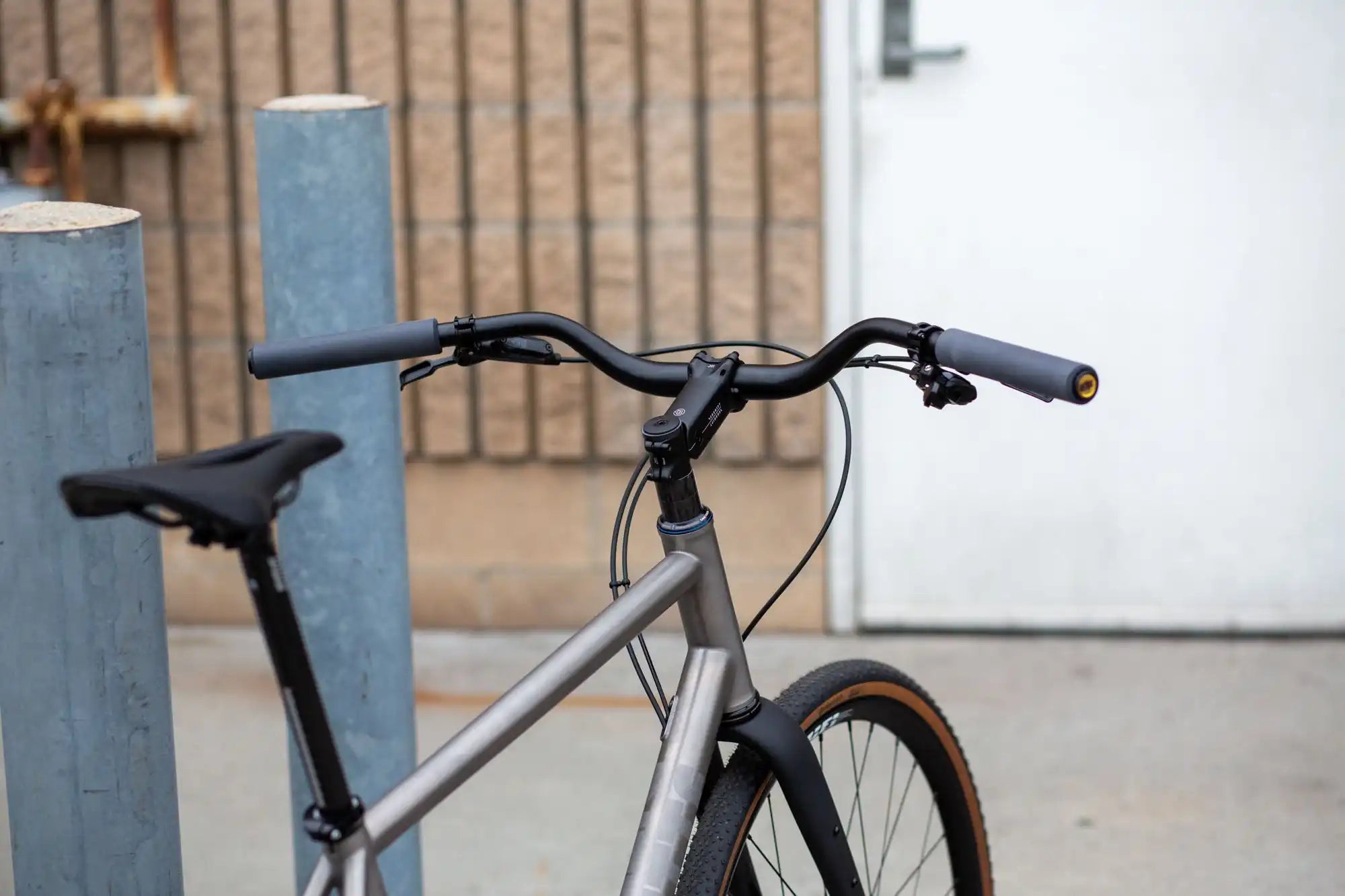 Gray bicycle with black handlebars and brown-walled tires.