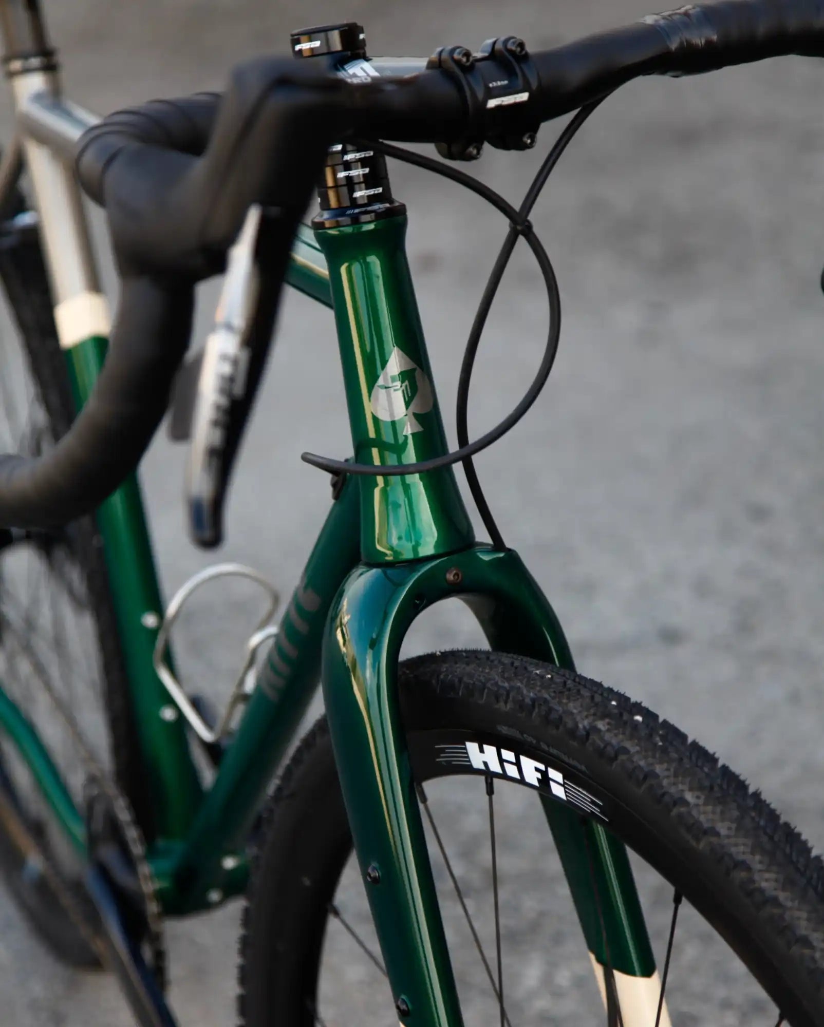 Green metallic bicycle frame with black handlebars and tires.