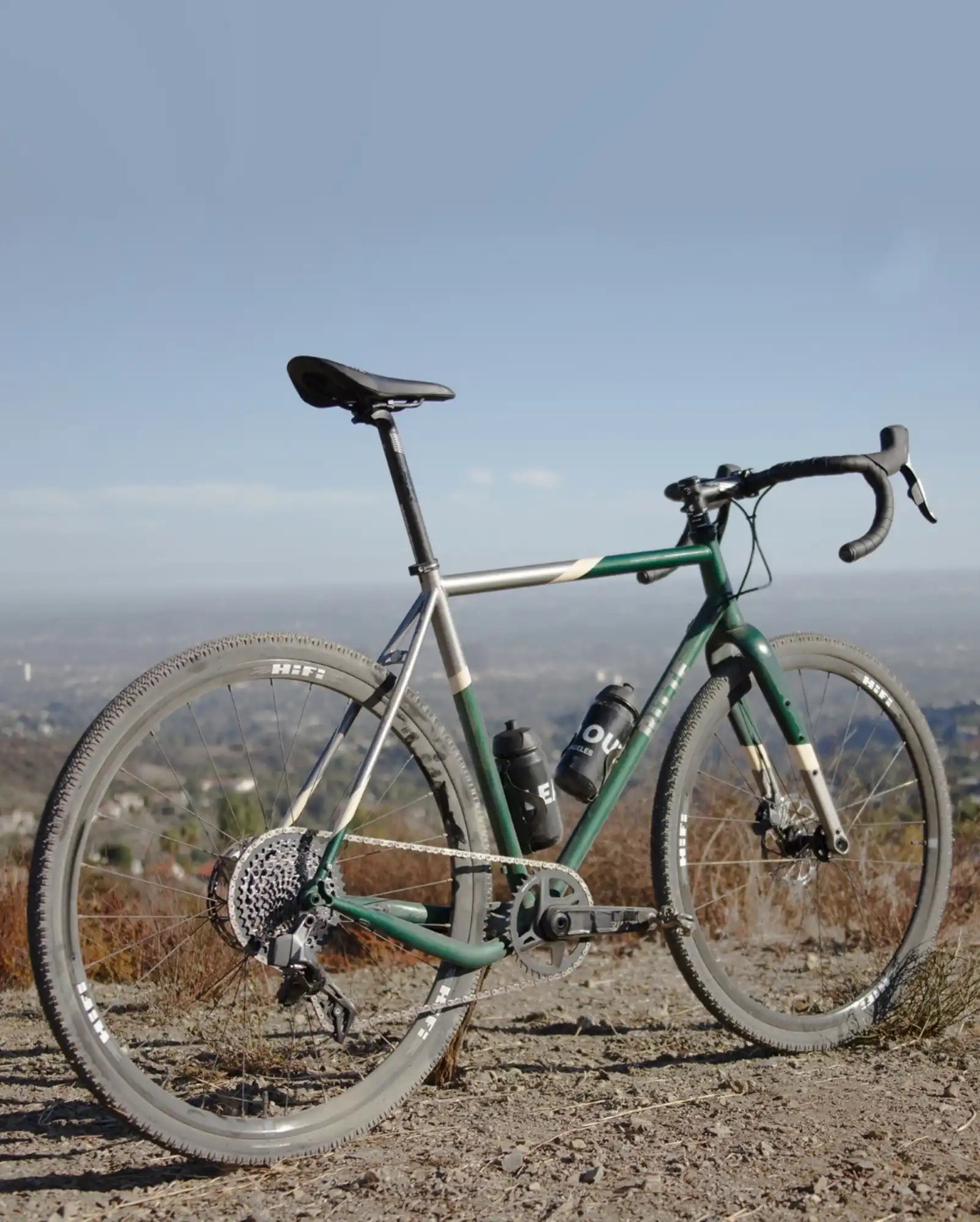 Green and silver road bicycle with drop handlebars and knobby tires.