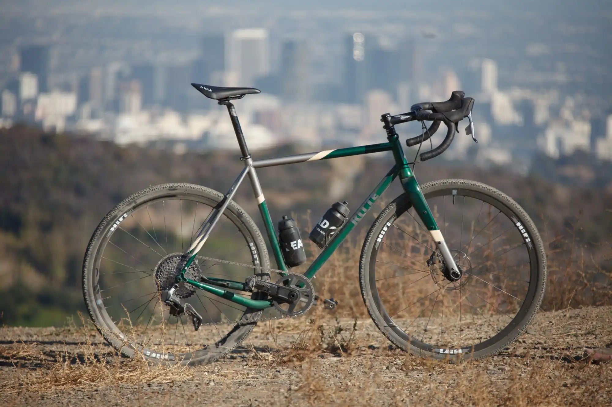 Green and silver road bike with disc brakes and drop handlebars.