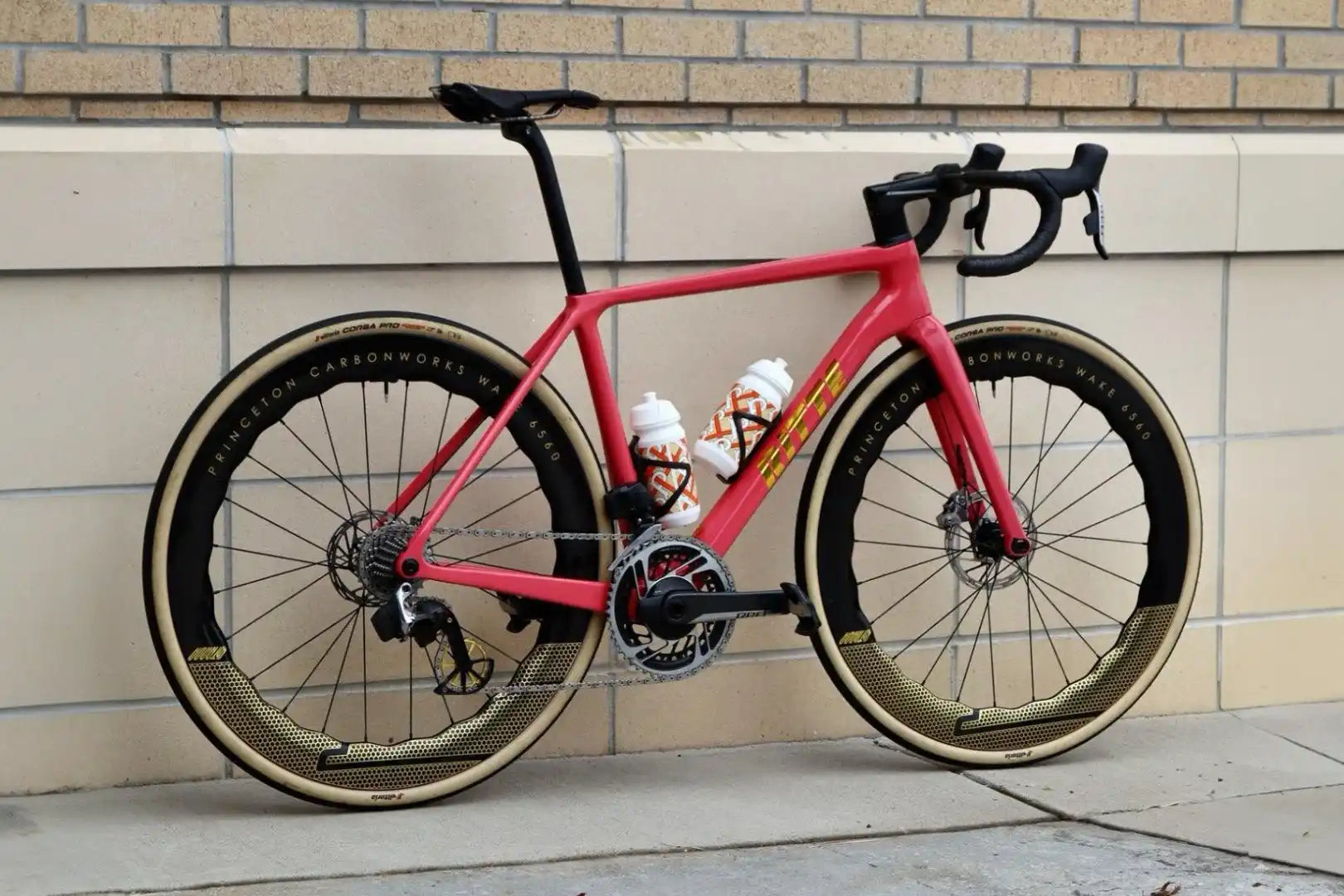 Hot pink road bike with disc brakes and black components.