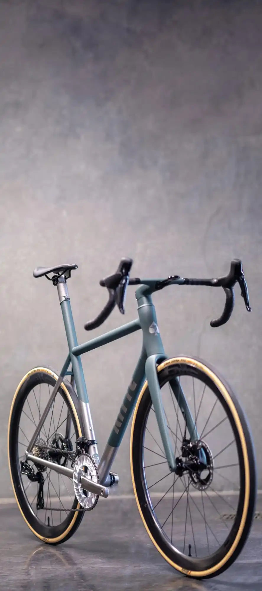 Light blue road bike with drop handlebars and tan sidewall tires.