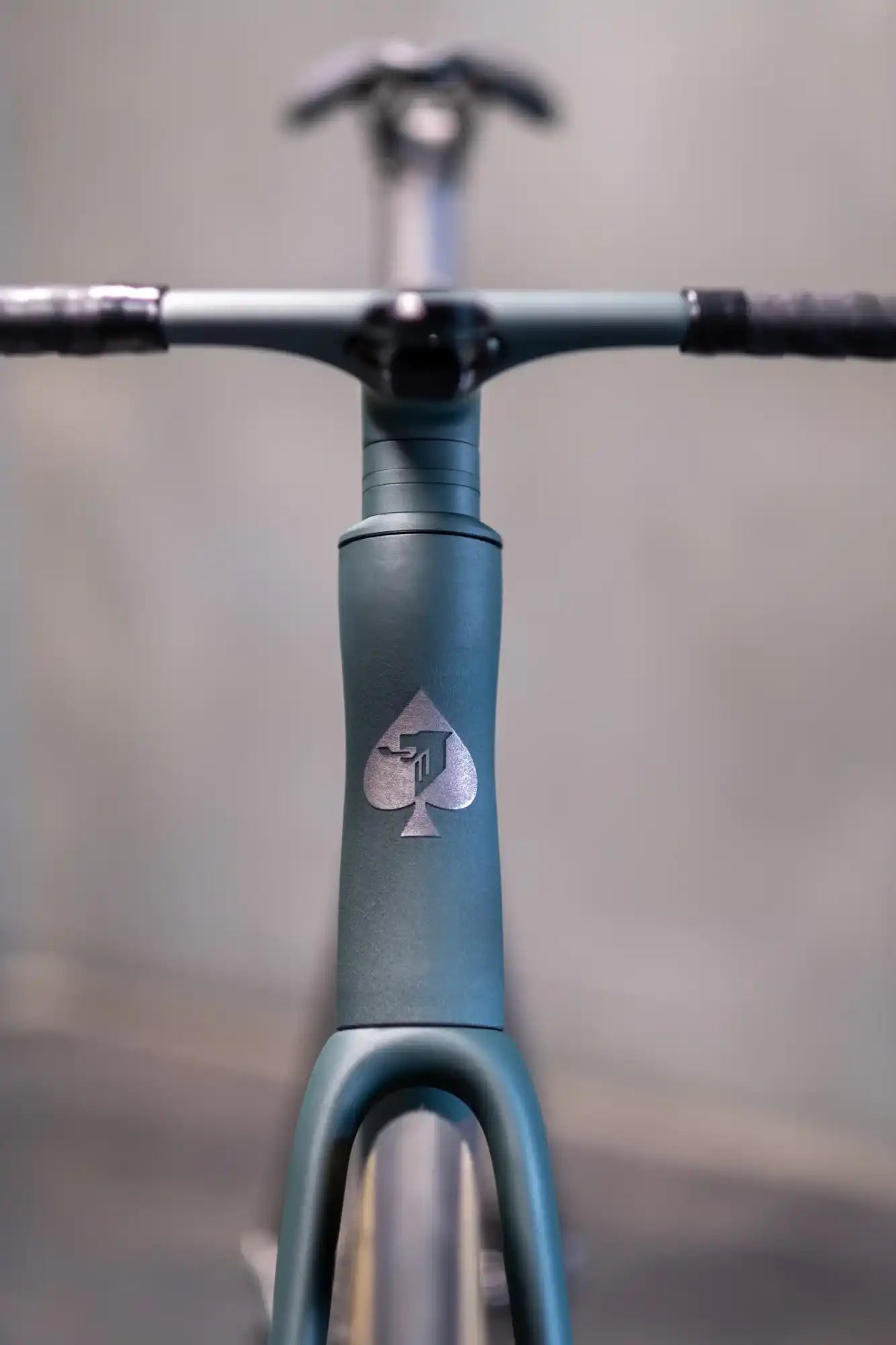 Matte gray bicycle frame with a spade symbol logo near the head tube.