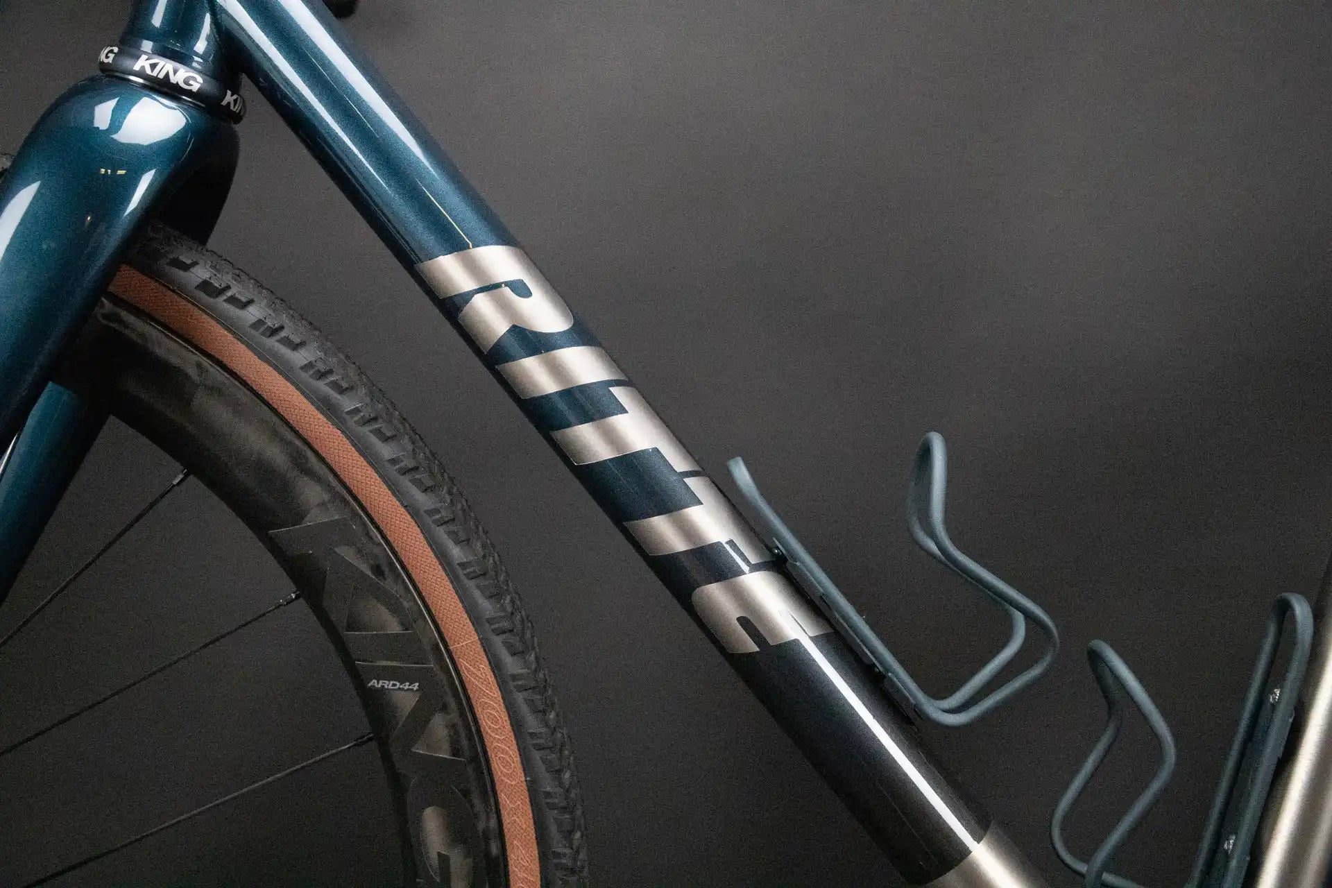 Metallic teal bicycle frame with striped silver accents and a gum-wall tire.