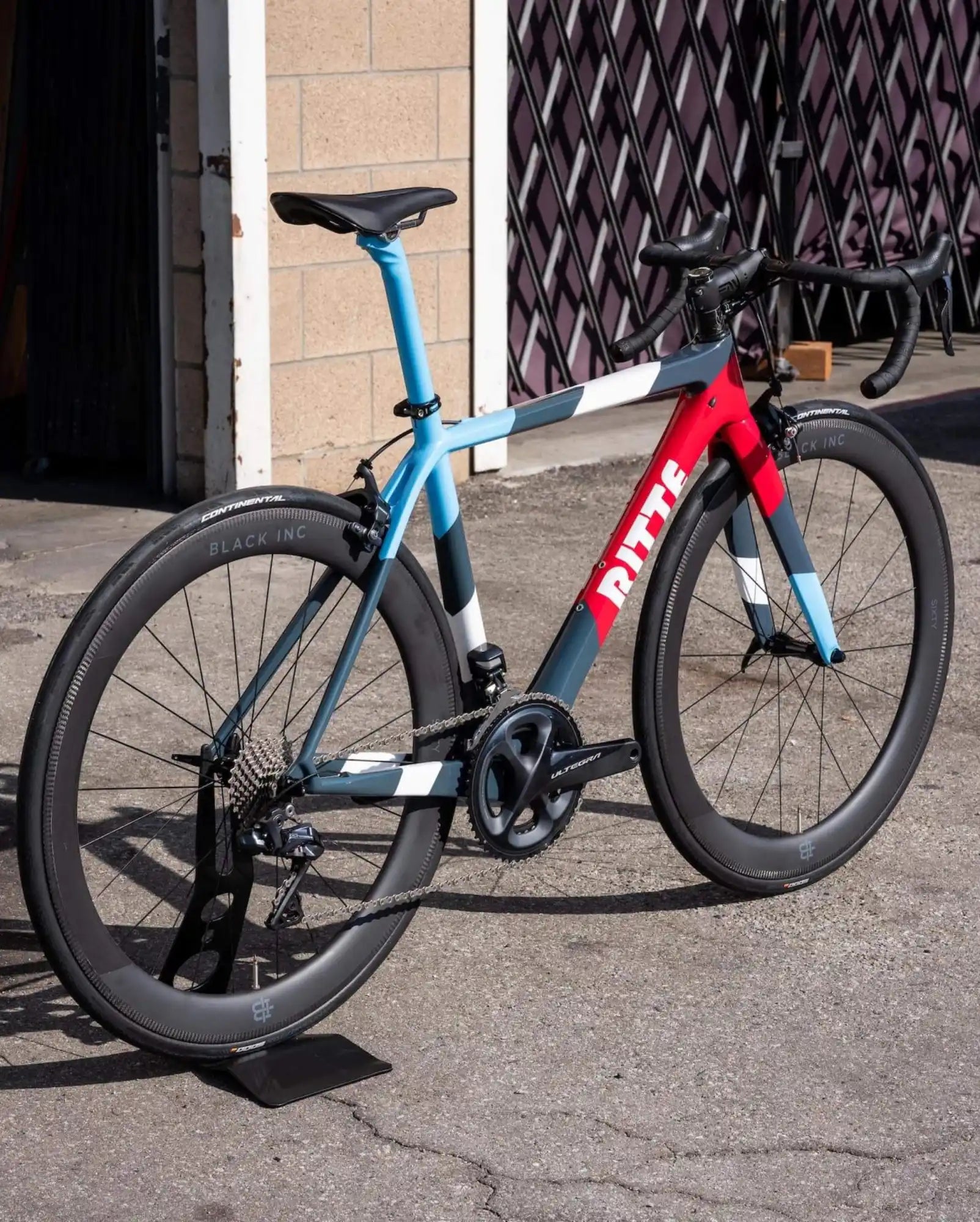 Modern racing bicycle with a blue and red frame and black wheels.