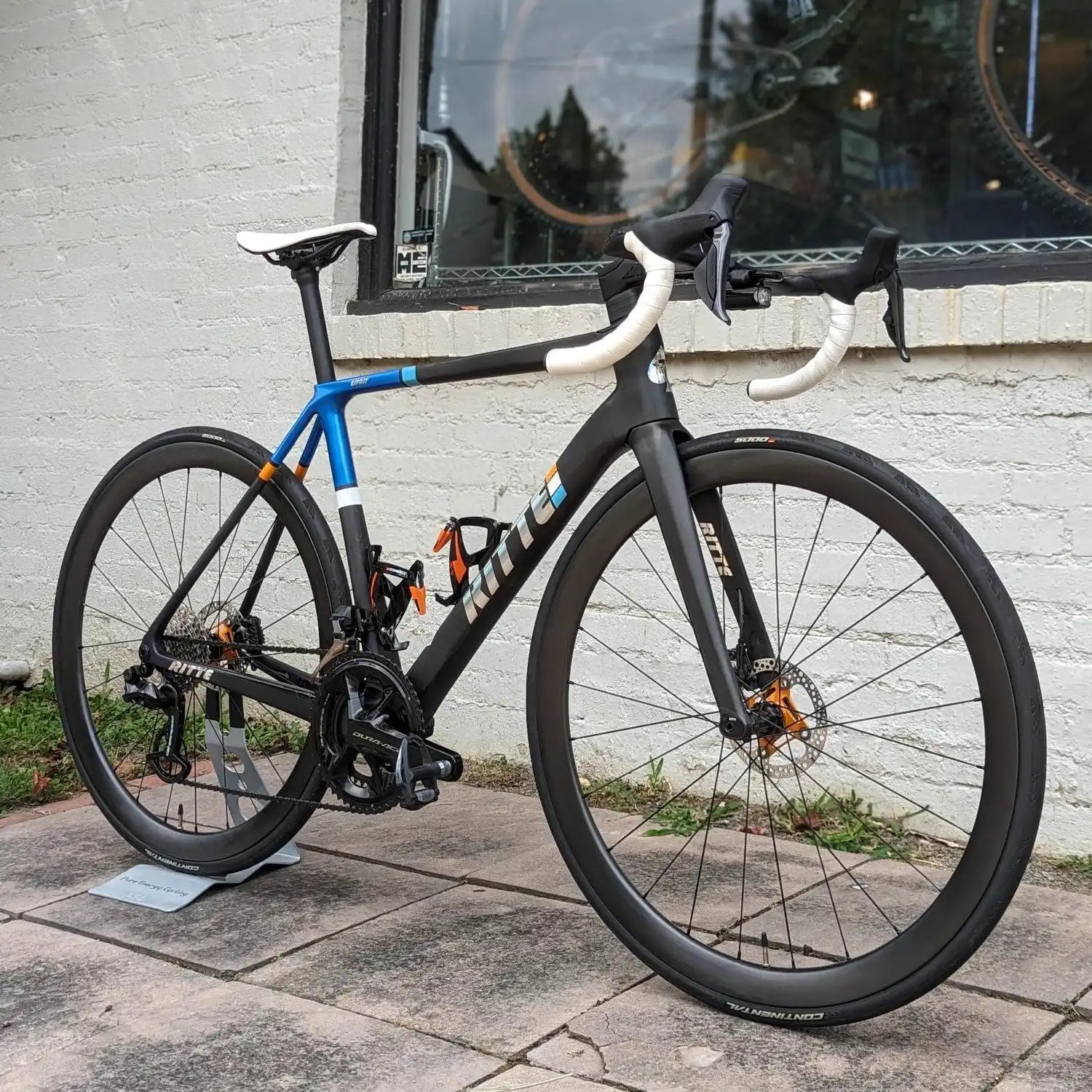 Modern road bike with black and blue frame, disc brakes, and white handlebars.