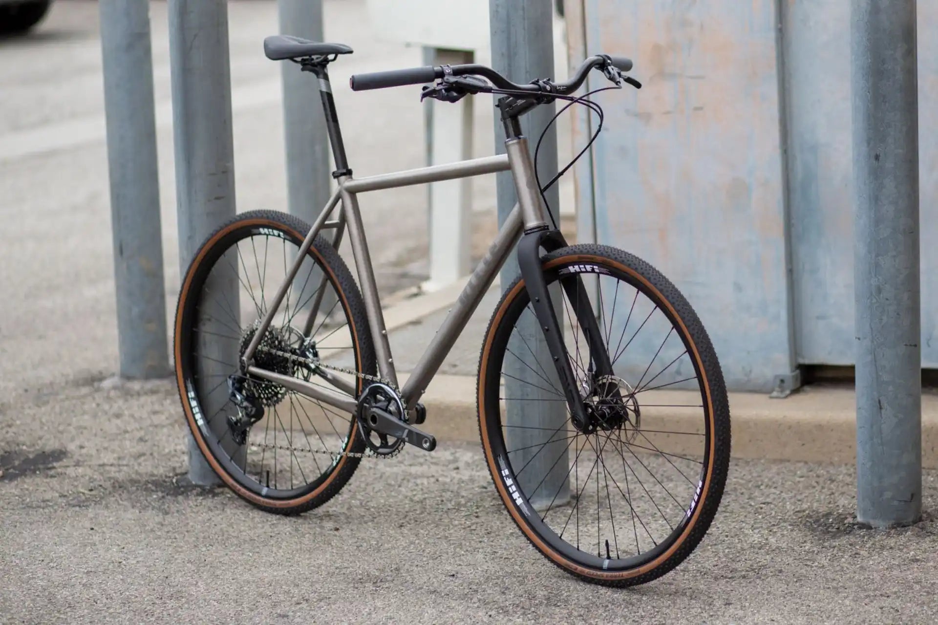 Modern urban bicycle with a sleek titanium frame and brown gumwall tires.