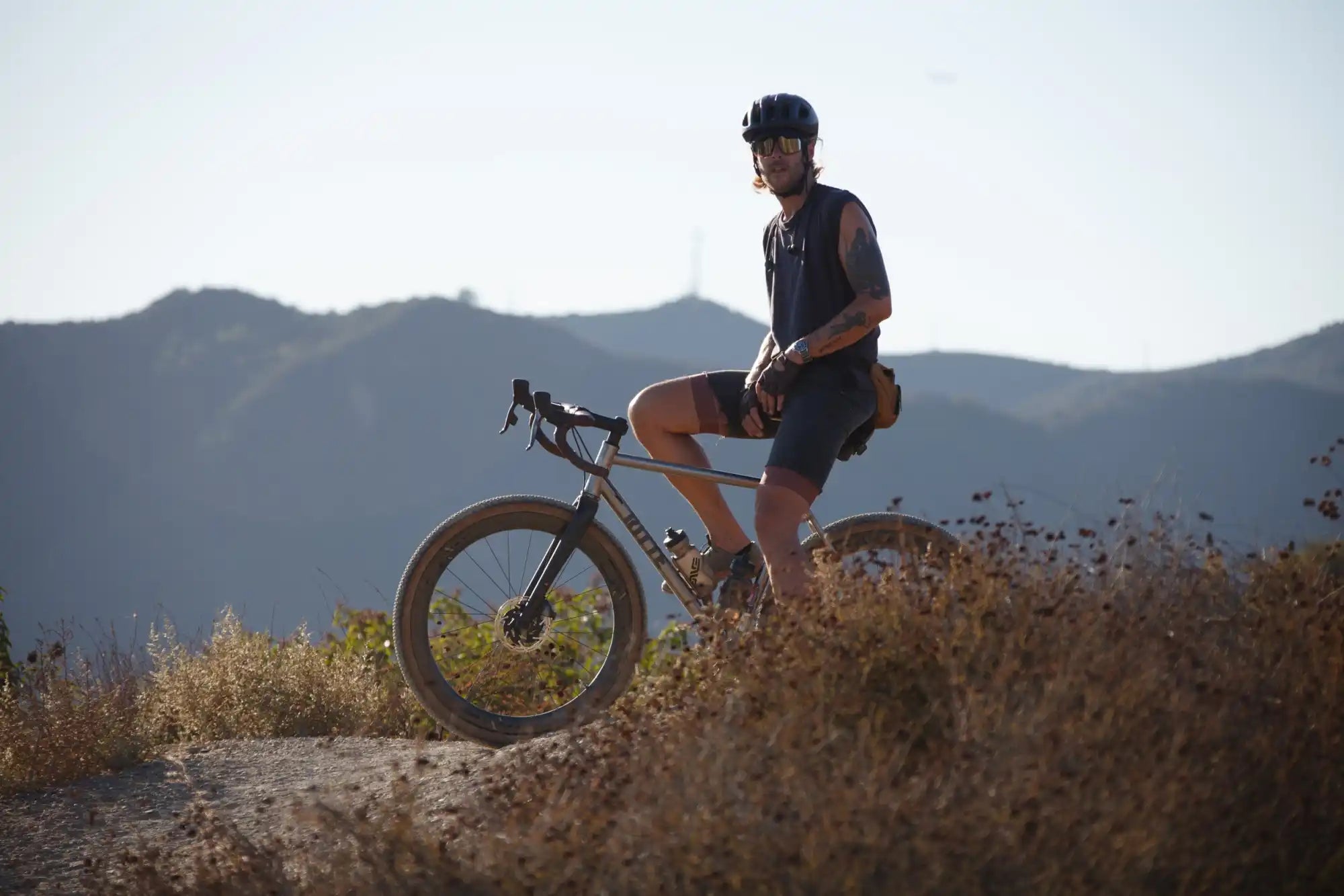 Mountain biker on a trail bike pausing at the crest of a hill.