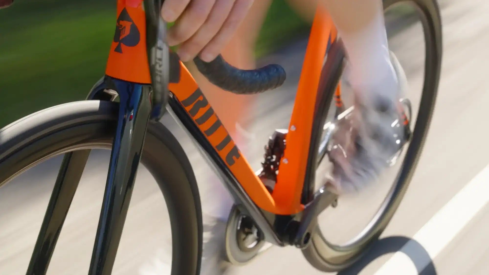 Orange and black road bicycle with curved handlebars.