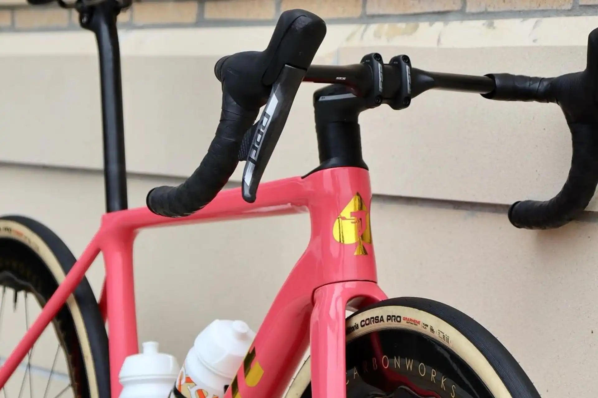 Pink racing bicycle with black handlebars.