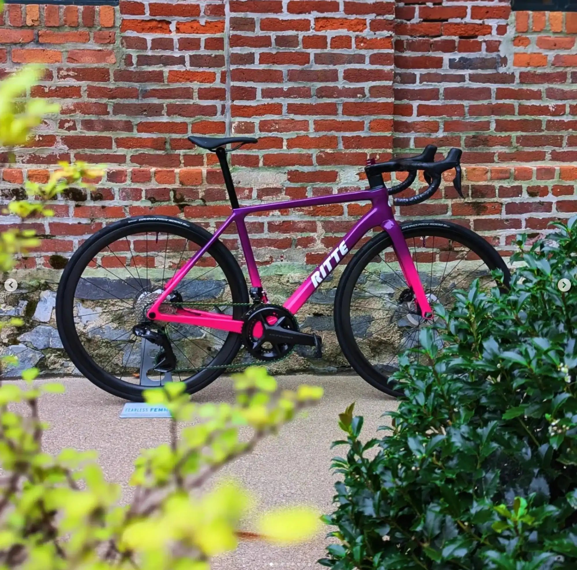 Pink and black road bicycle with drop handlebars.