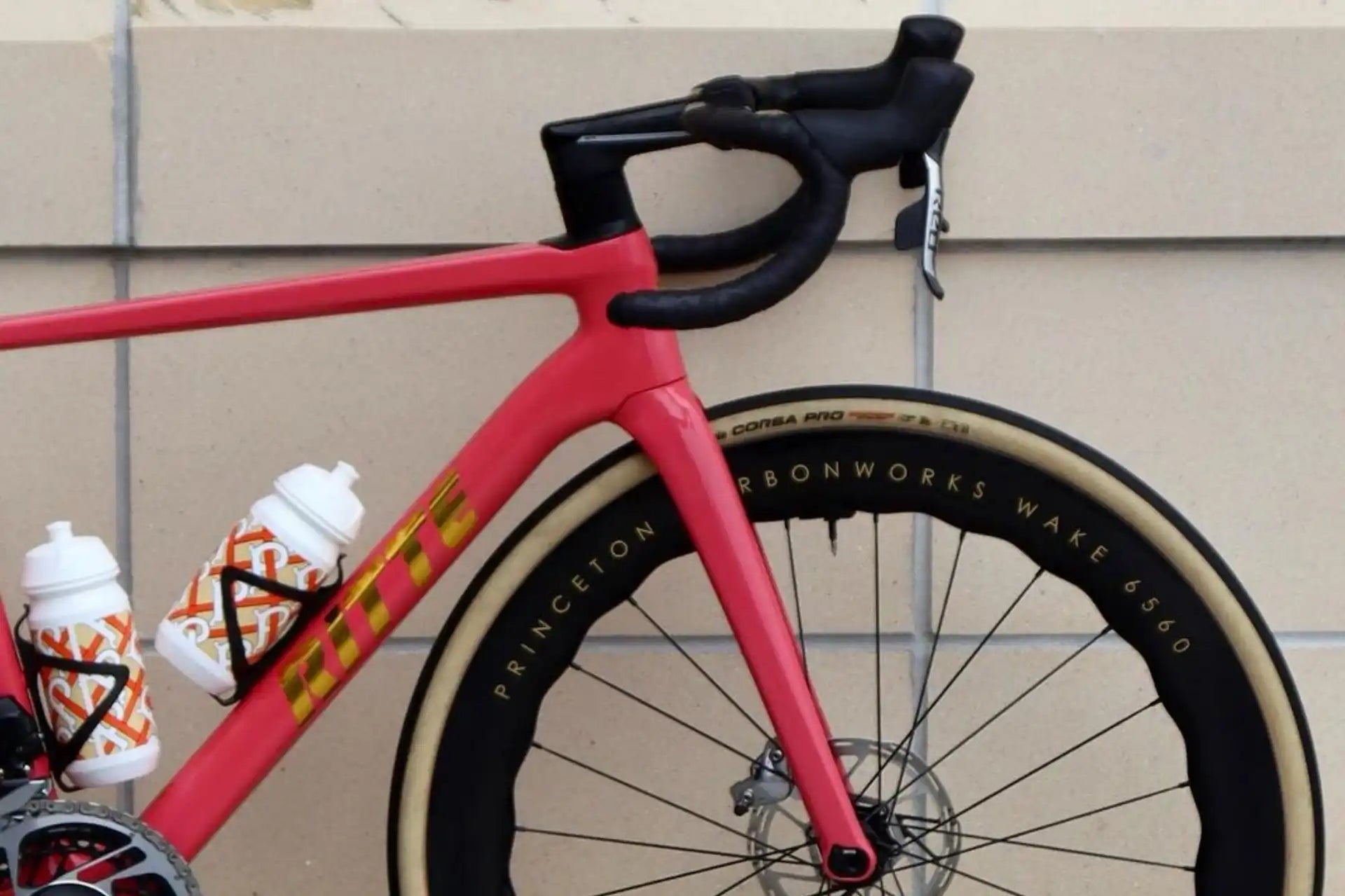 Pink road bicycle with black handlebars and disc brakes.