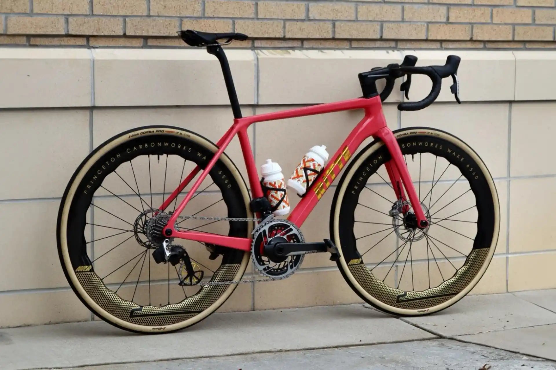 Pink road bike with disc brakes and drop handlebars.