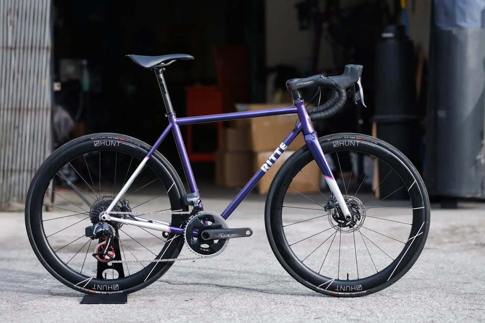 Purple and white road bike with disc brakes and drop handlebars.