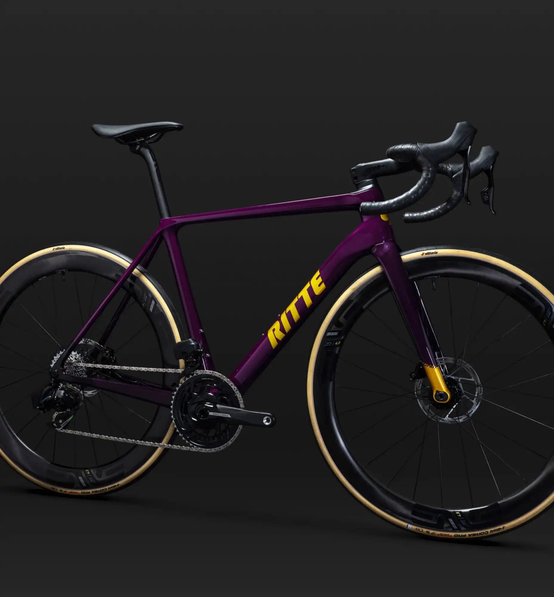 Purple and yellow road bike with disc brakes and tan sidewall tires.