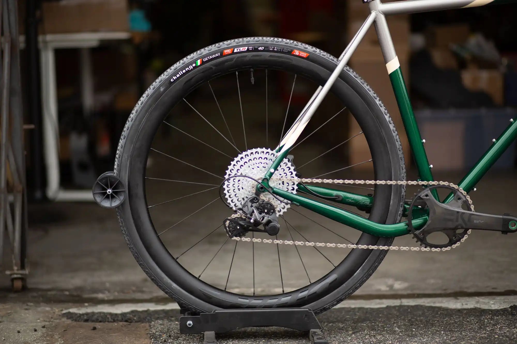 Rear wheel and drivetrain of a green bicycle with a black rim and silver cassette.