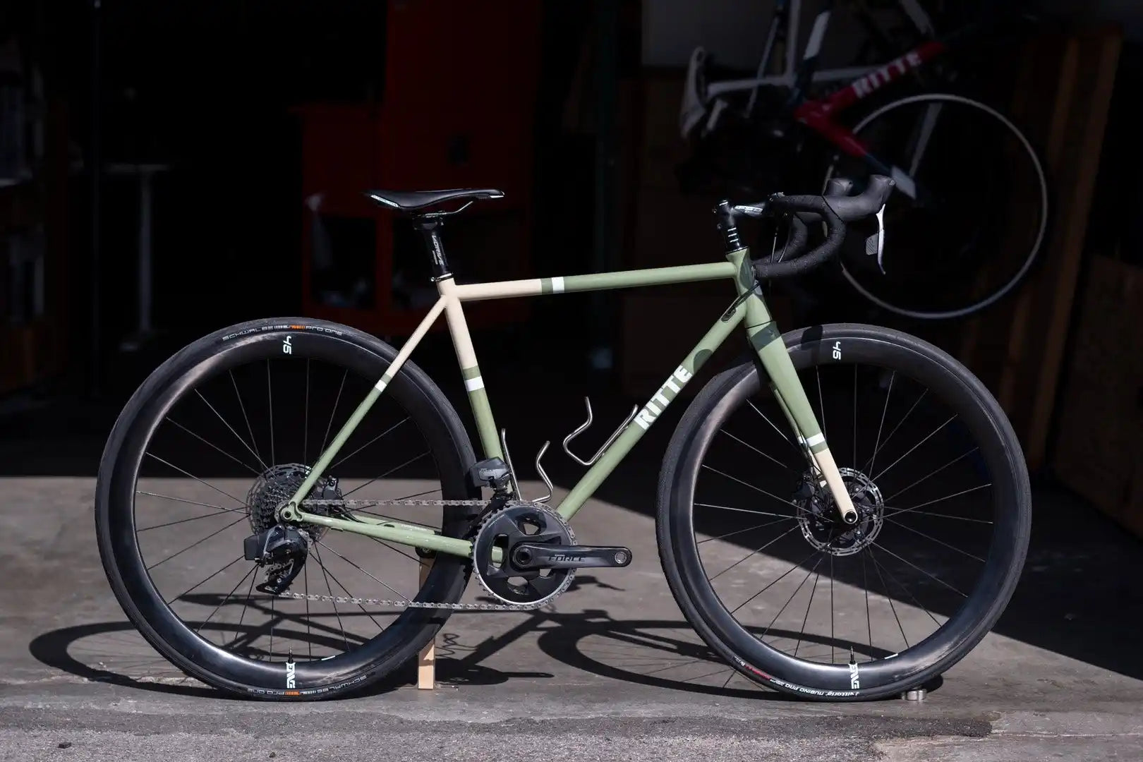 Sage green road bike with disc brakes and drop handlebars.