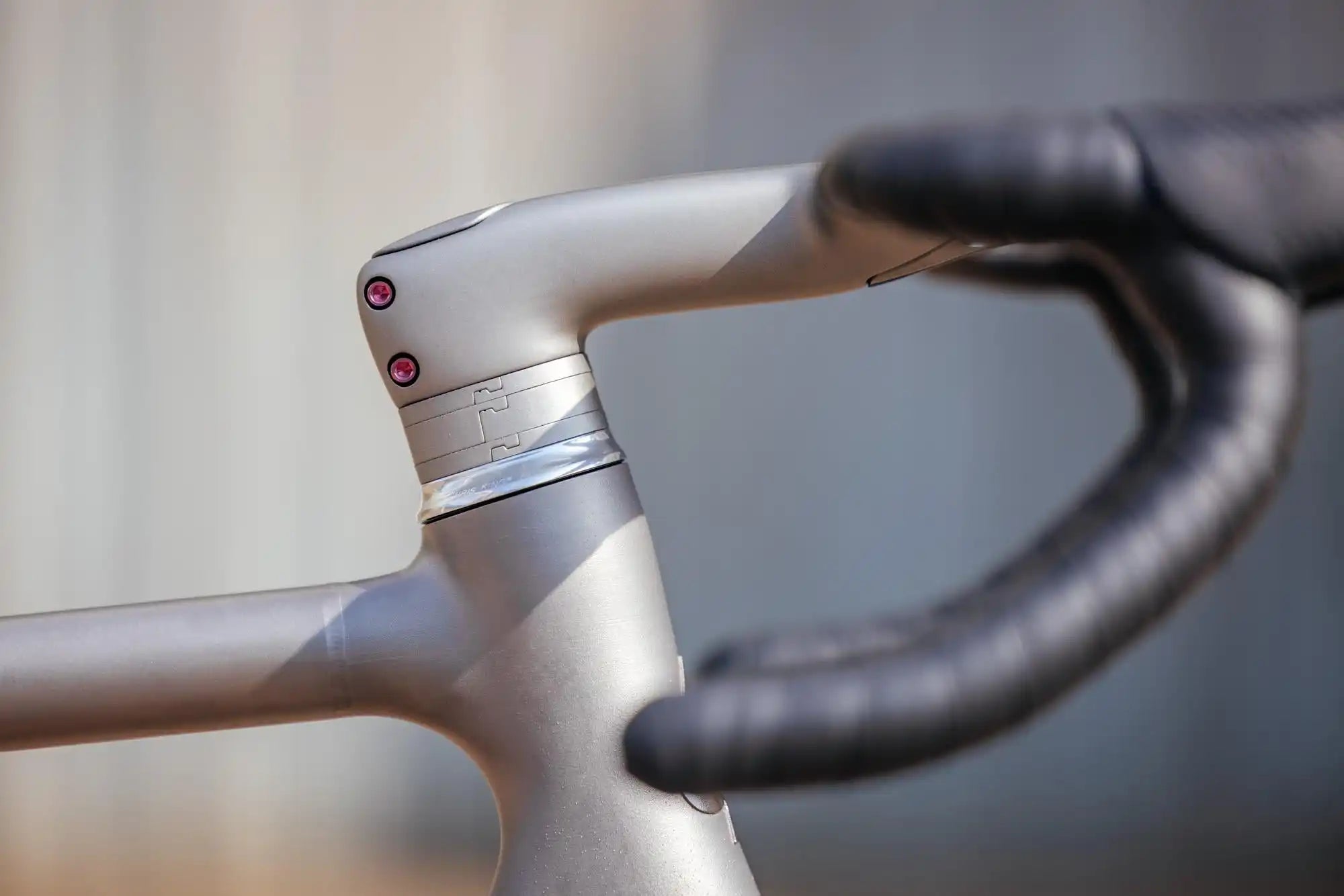 Silver bicycle handlebar and stem with black handlebar tape.