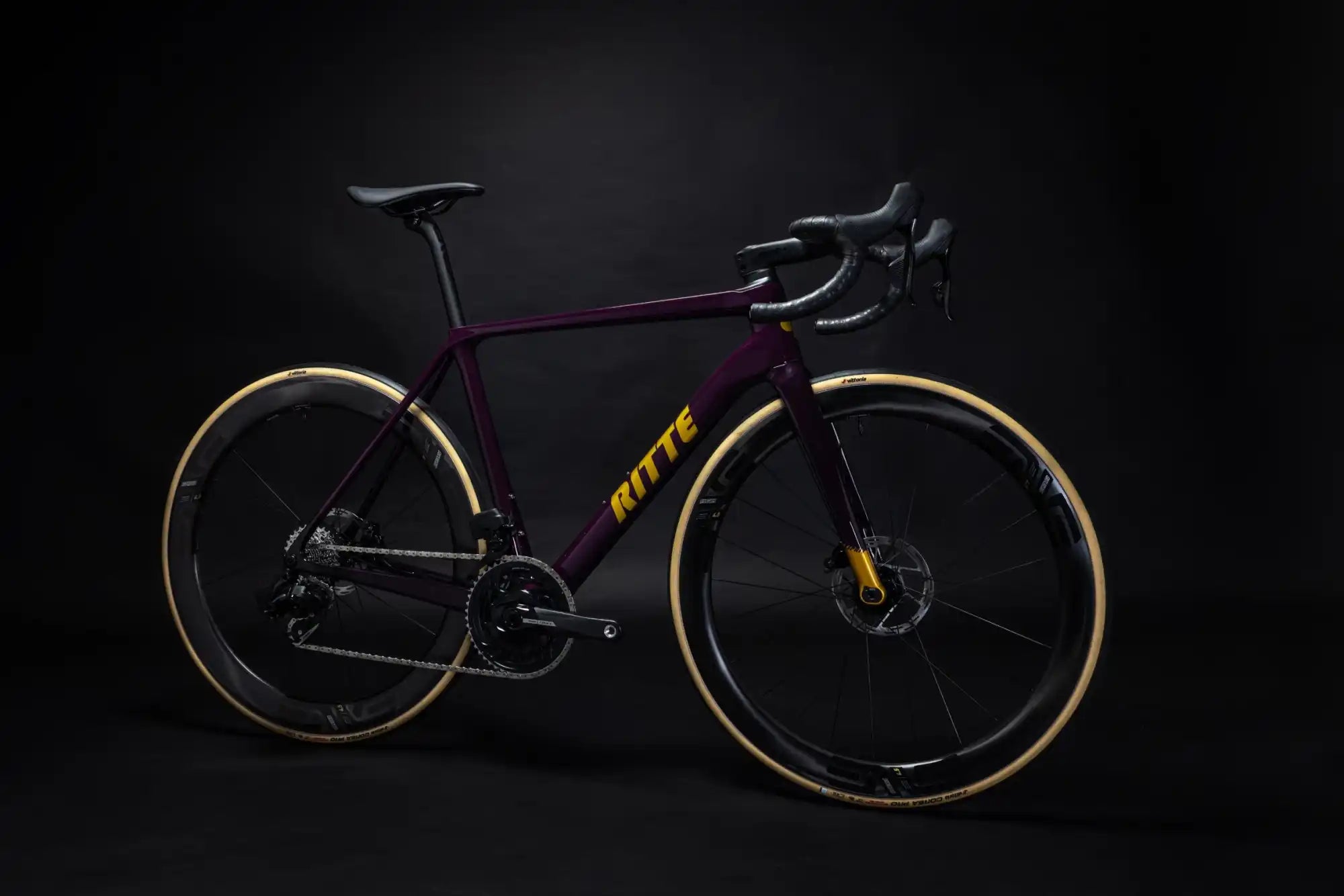 Sleek purple and black road bike with tan sidewall tires and disc brakes.