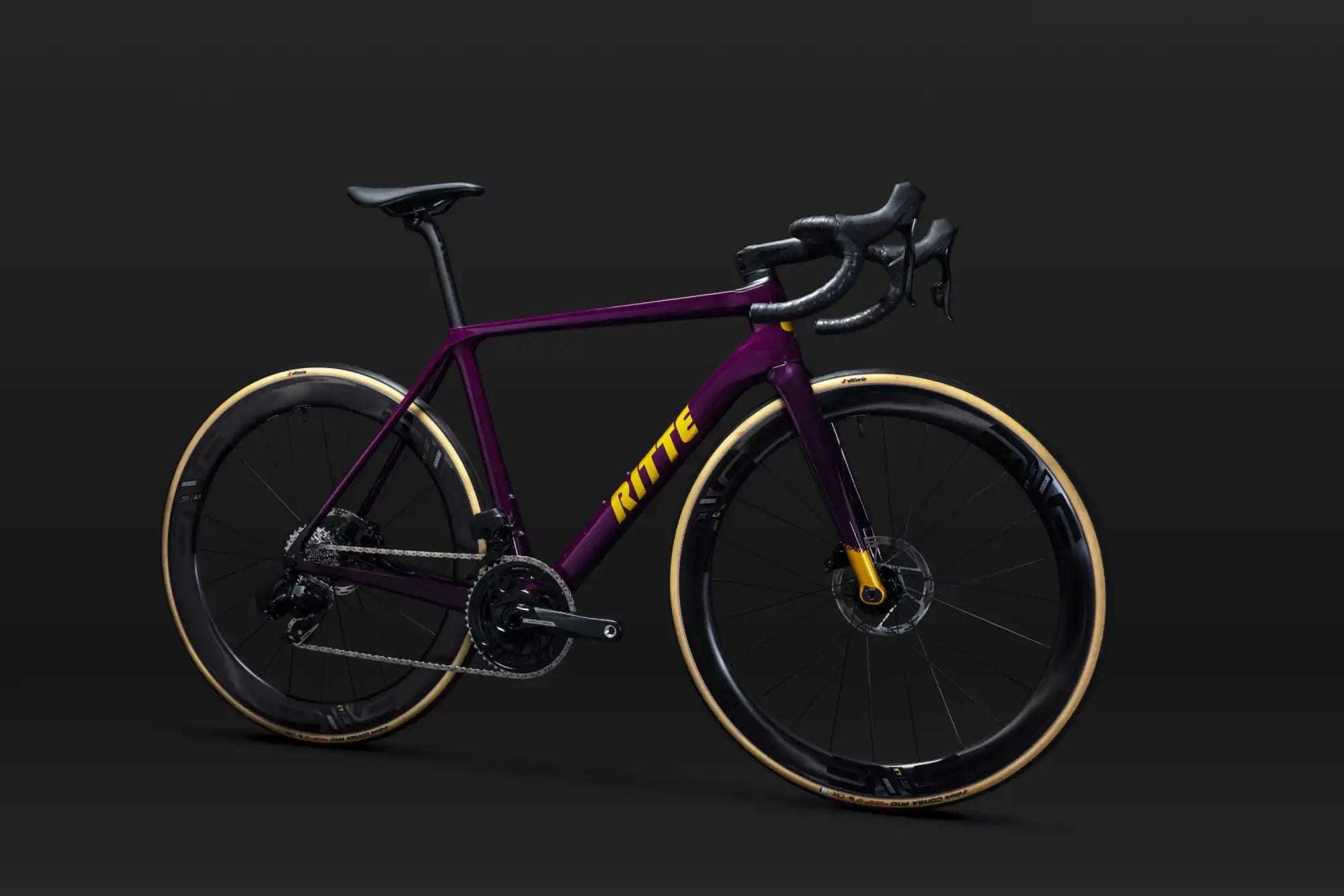 Sleek purple road bike with black handlebars and tan sidewall tires.