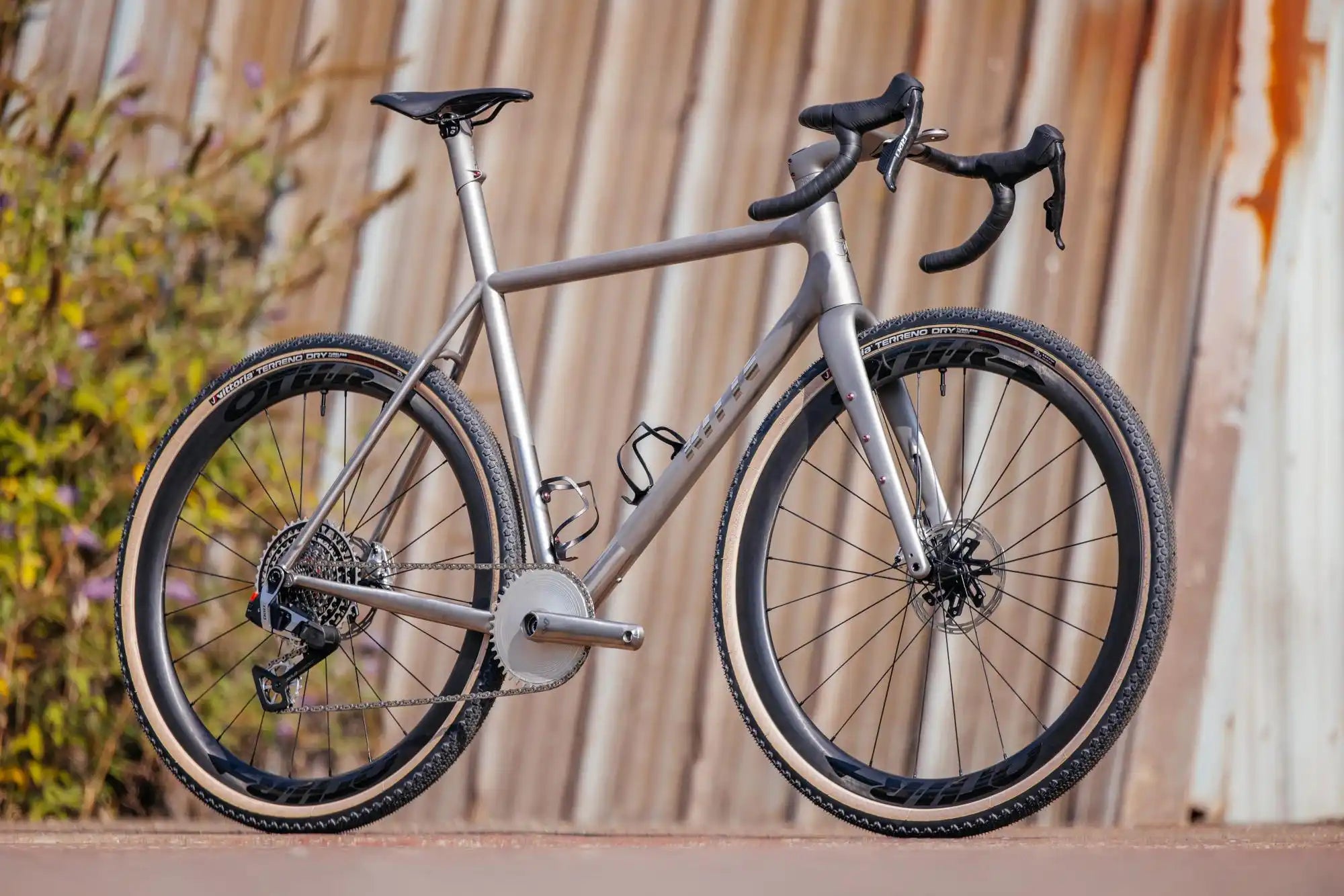 Sleek titanium road bike with disc brakes and drop handlebars.