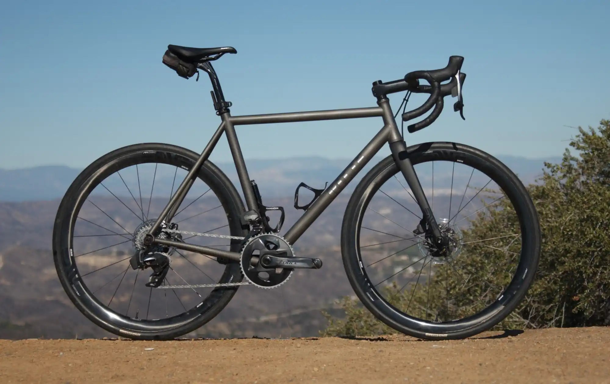 Sleek titanium road bike with drop handlebars and disc brakes.