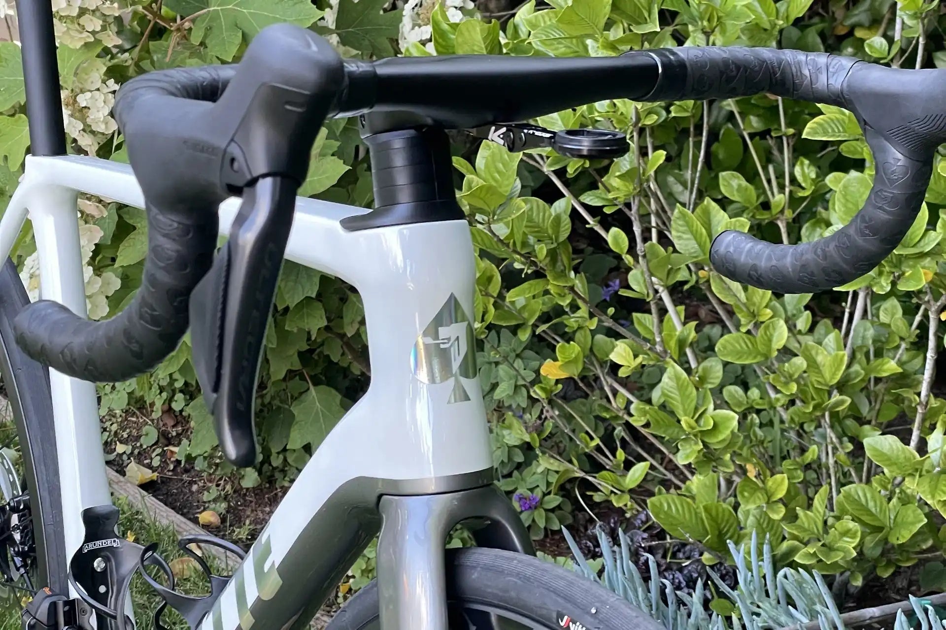 White road bike with black handlebar tape and drop bars.